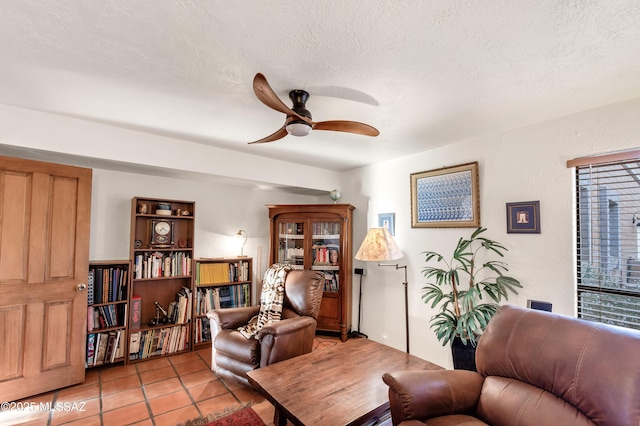 sitting room featuring tile patterned flooring, a ceiling fan, and a textured ceiling