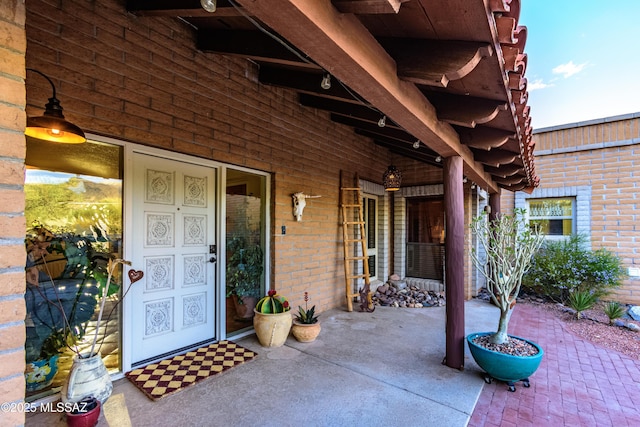 view of exterior entry with a porch and brick siding