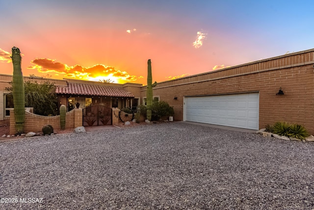 view of front of home with brick siding, fence, an attached garage, and driveway