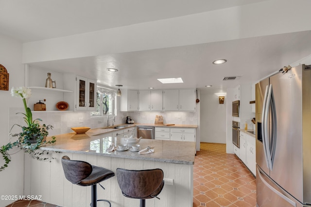 kitchen featuring visible vents, open shelves, a peninsula, a skylight, and stainless steel appliances