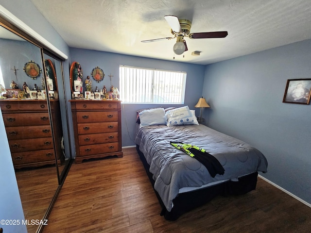 bedroom with baseboards, ceiling fan, wood finished floors, and a closet