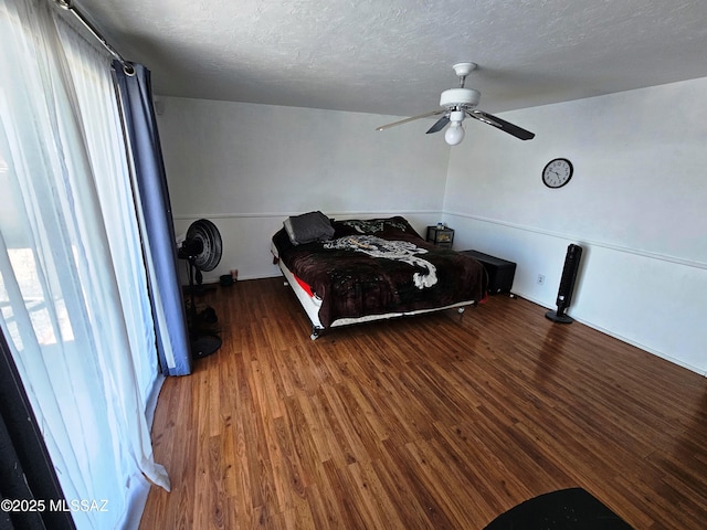 bedroom with a ceiling fan, a textured ceiling, and wood finished floors
