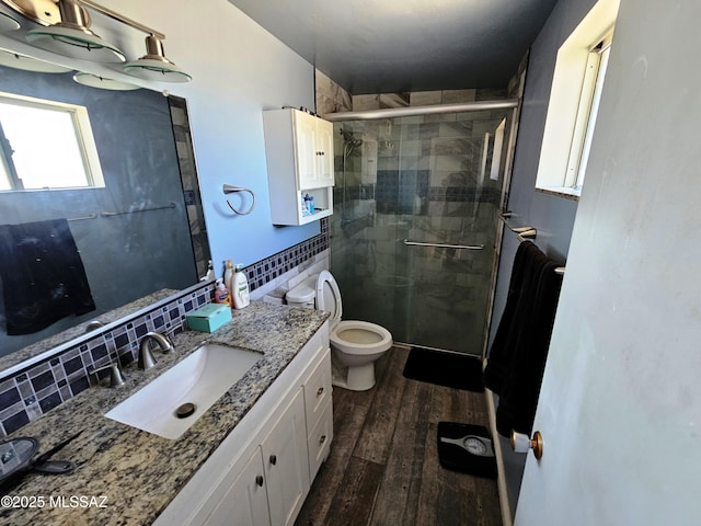 full bath featuring vanity, toilet, a shower stall, wood finished floors, and tasteful backsplash