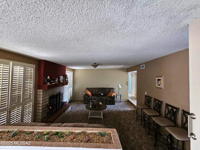 living room featuring carpet flooring, a textured ceiling, visible vents, and a fireplace