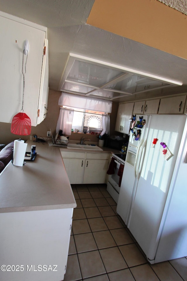 kitchen with white cabinetry, a peninsula, light tile patterned flooring, and white appliances