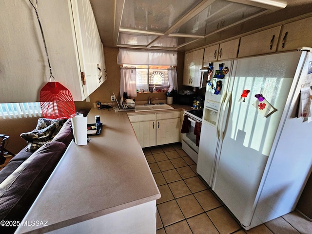 kitchen featuring white appliances, a sink, tile patterned flooring, and light countertops