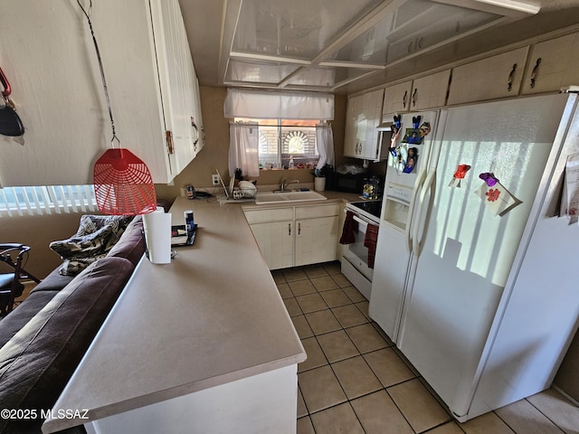 kitchen featuring a sink, light tile patterned floors, light countertops, white appliances, and white cabinetry