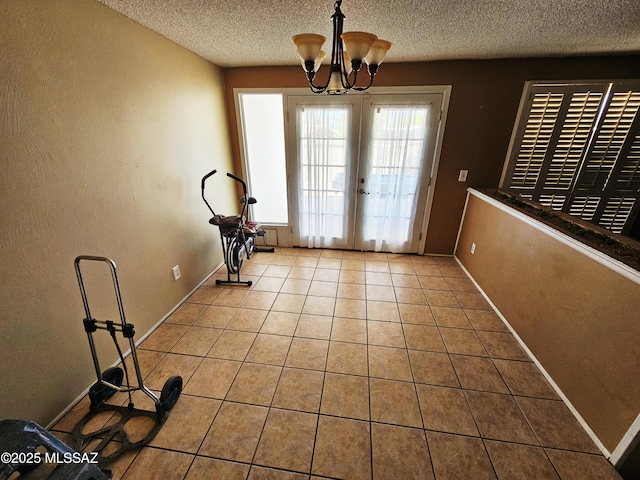 doorway with french doors, a textured ceiling, tile patterned floors, baseboards, and a chandelier