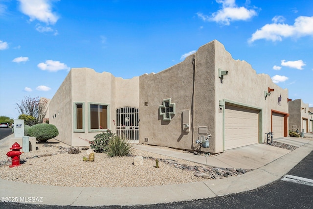 adobe home featuring concrete driveway, stucco siding, and a garage