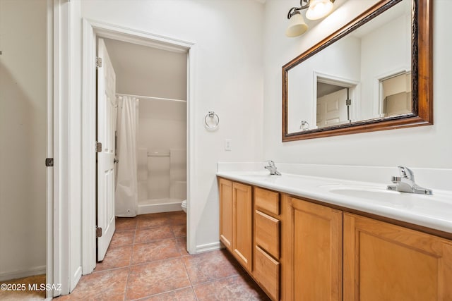 bathroom featuring double vanity, toilet, a shower with curtain, a sink, and tile patterned flooring