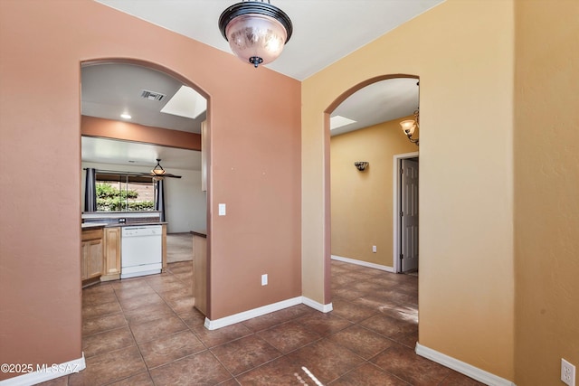 hall featuring arched walkways, baseboards, dark tile patterned flooring, and visible vents
