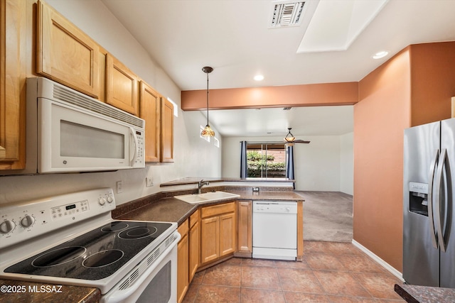 kitchen featuring a peninsula, a sink, dark countertops, pendant lighting, and white appliances