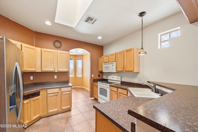 kitchen featuring white appliances, light brown cabinetry, visible vents, and dark countertops