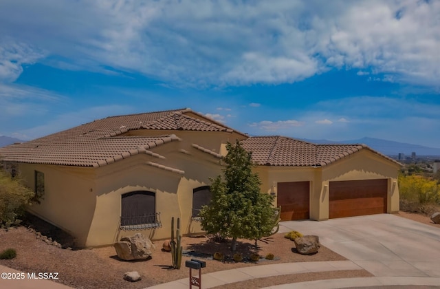 mediterranean / spanish house with concrete driveway, stucco siding, a tiled roof, and an attached garage