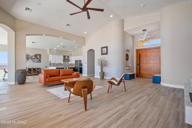 living area featuring arched walkways, ceiling fan, visible vents, and high vaulted ceiling