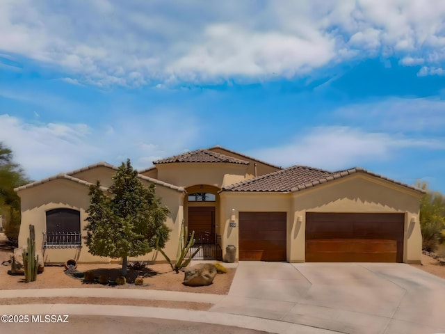 mediterranean / spanish home with a tiled roof, stucco siding, driveway, and a garage