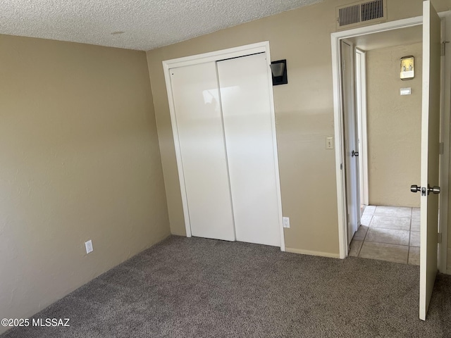 unfurnished bedroom featuring carpet, a closet, a textured ceiling, and visible vents