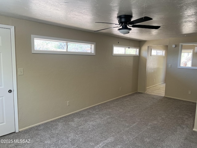 carpeted empty room featuring baseboards, ceiling fan, and a healthy amount of sunlight