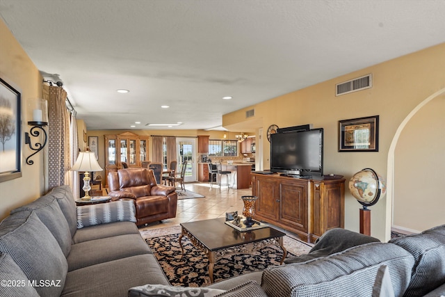 living area featuring light tile patterned floors, arched walkways, recessed lighting, and visible vents