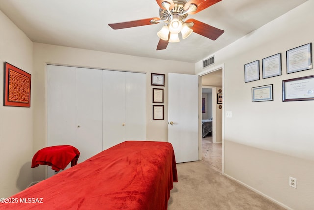 bedroom featuring light colored carpet, ceiling fan, visible vents, and a closet