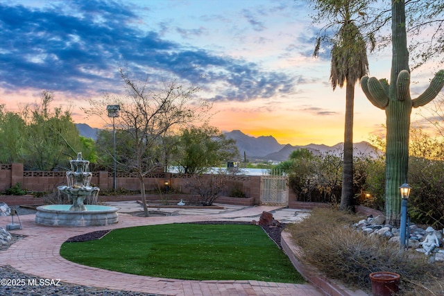yard at dusk with a mountain view and fence
