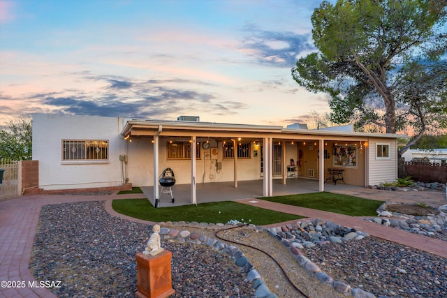 rear view of property featuring stucco siding, a patio area, and fence
