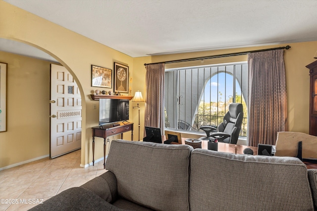 living area featuring arched walkways, baseboards, and light tile patterned floors