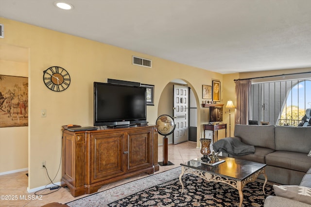 living room featuring arched walkways, baseboards, light tile patterned flooring, and visible vents