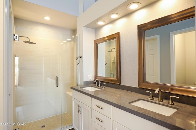 bathroom with recessed lighting, a sink, double vanity, and a shower stall