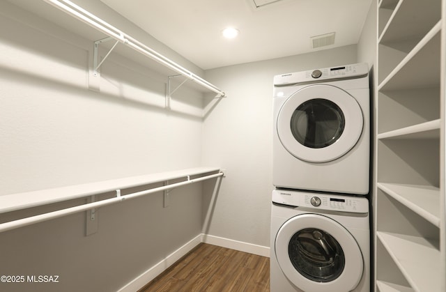 washroom featuring laundry area, stacked washer and dryer, dark wood-style flooring, visible vents, and baseboards