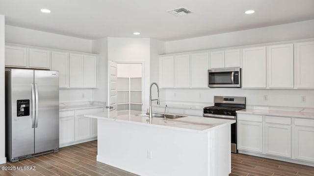 kitchen with visible vents, appliances with stainless steel finishes, wood finish floors, a sink, and white cabinets