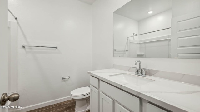 full bath featuring vanity, toilet, baseboards, wood finished floors, and a shower