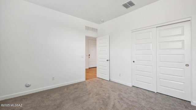 unfurnished bedroom with carpet floors, baseboards, visible vents, and a closet