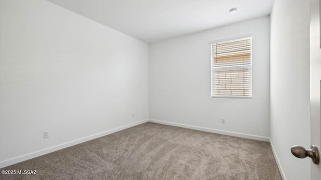 spare room featuring baseboards and carpet