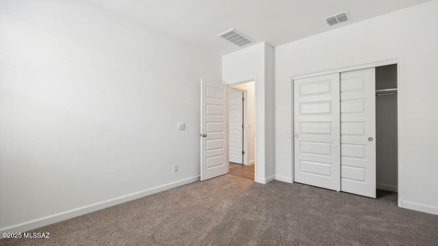 unfurnished bedroom with baseboards, visible vents, carpet, and a closet