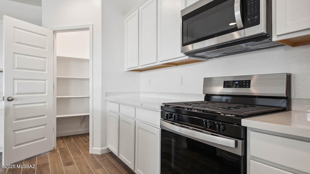 kitchen with light countertops, white cabinets, stainless steel appliances, and wood finish floors