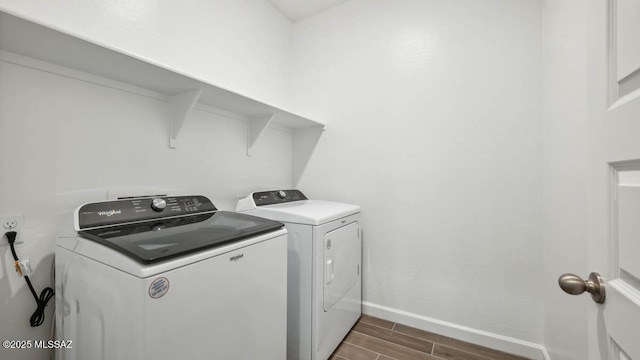 laundry area featuring laundry area, baseboards, wood finish floors, and washer and dryer