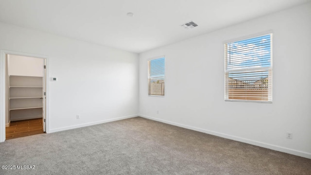 unfurnished bedroom with carpet floors, baseboards, visible vents, and multiple windows