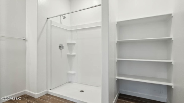 full bathroom featuring wood finished floors, baseboards, and a stall shower