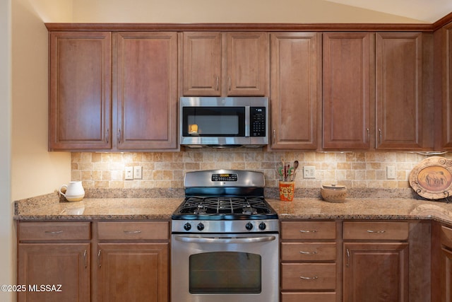 2740 E Ponce Ct, Green Valley, AZ 85614 - kitchen with stainless steel appliances, backsplash, light stone counters, and brown cabinets