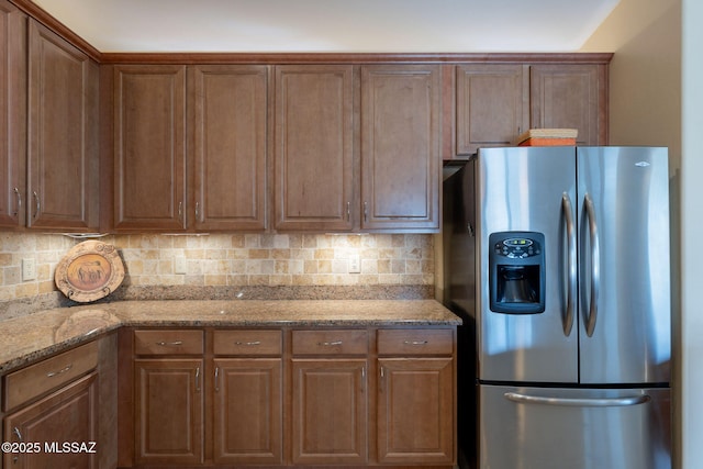 2740 E Ponce Ct, Green Valley, AZ 85614 - kitchen featuring stainless steel fridge with ice dispenser, tasteful backsplash, light stone counters, and brown cabinets