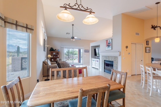 2740 E Ponce Ct, Green Valley, AZ 85614 - dining space with high vaulted ceiling, a fireplace, ceiling fan, light tile patterned floors, and baseboards