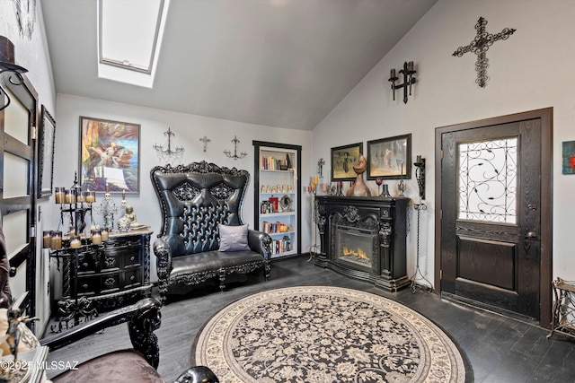 living area with a glass covered fireplace, wood finished floors, and vaulted ceiling with skylight