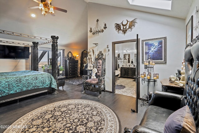 bedroom with vaulted ceiling with skylight, ensuite bath, and wood finished floors