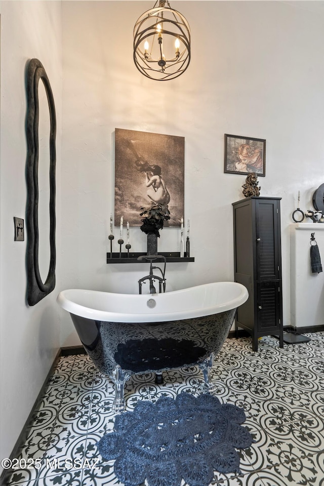 bathroom with baseboards, a soaking tub, and a notable chandelier