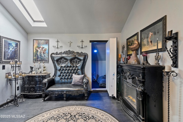 living area featuring wood finished floors and vaulted ceiling with skylight