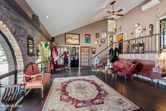living area with ceiling fan, a wall mounted air conditioner, high vaulted ceiling, hardwood / wood-style floors, and stairway