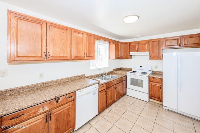 kitchen with a sink, white appliances, brown cabinets, under cabinet range hood, and light tile patterned floors
