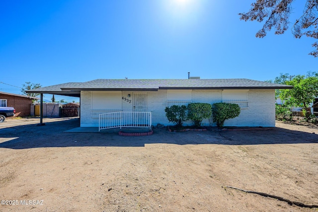 back of house with fence, brick siding, and an attached carport