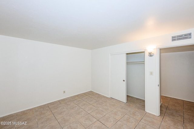 unfurnished bedroom featuring light tile patterned floors, a closet, and visible vents